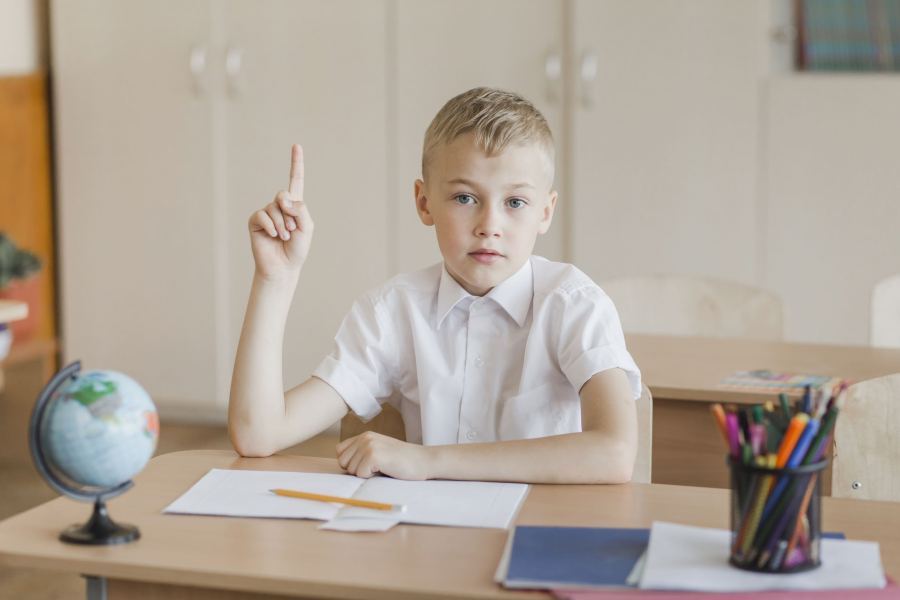 boy-sitting-classroom-raising-finger.jpg