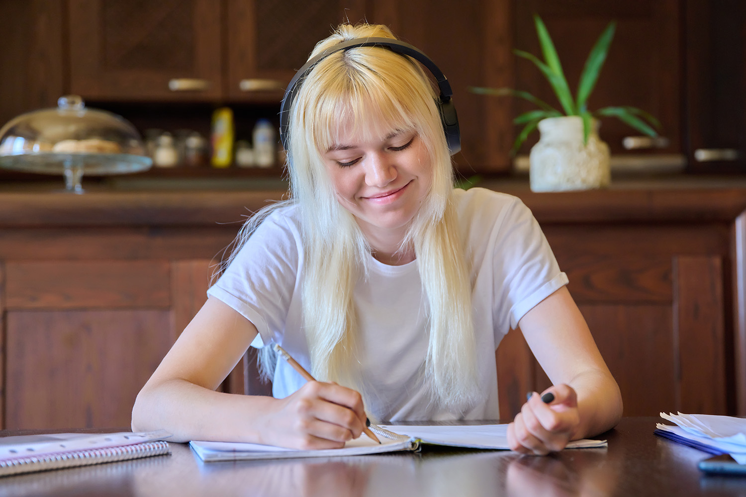 portrait_teenage_student_girl_headphones_studying_home_sitting_table.jpg
