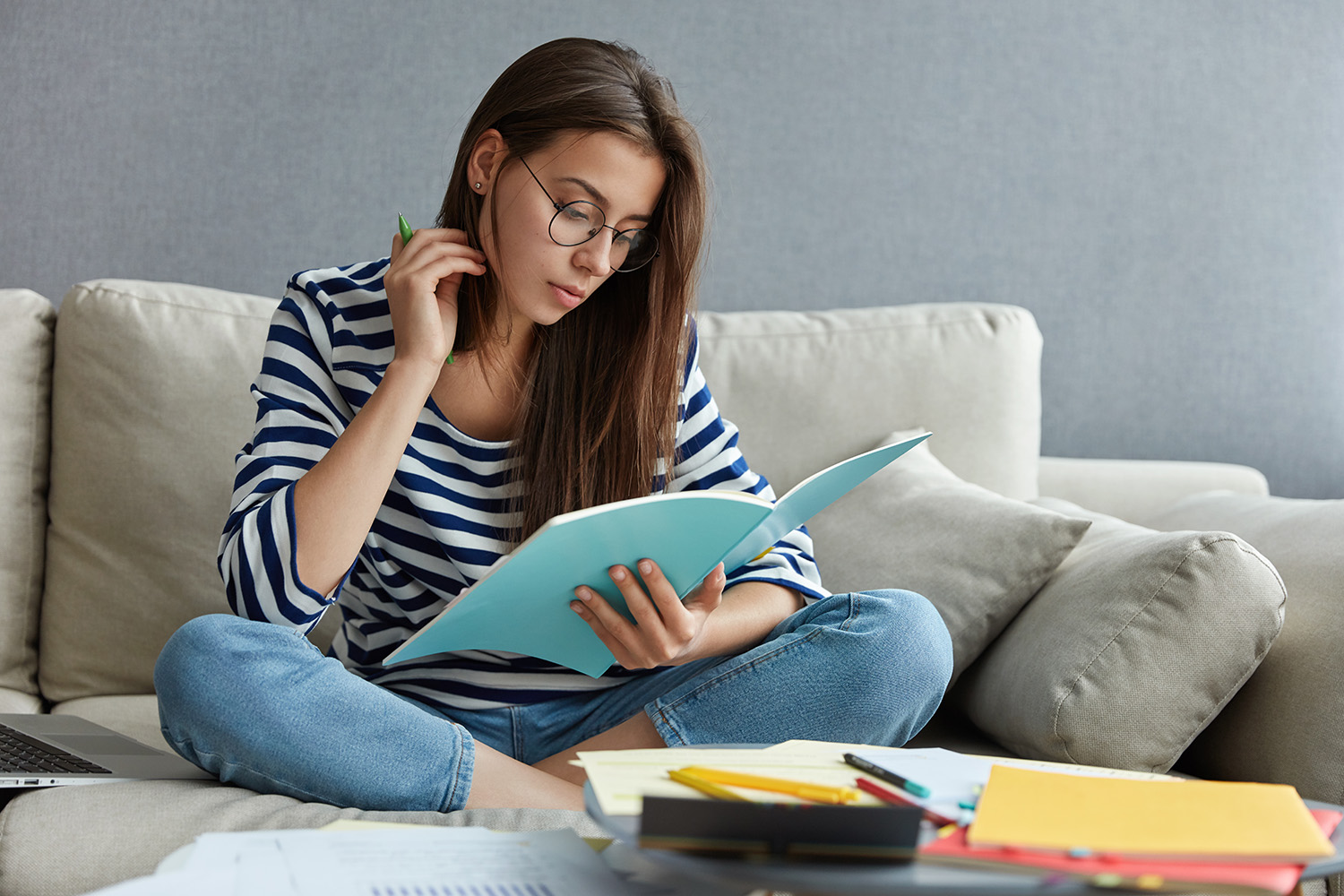 dark_haired_attractive_woman_reading_textbook_surrounded_with_papers.jpg