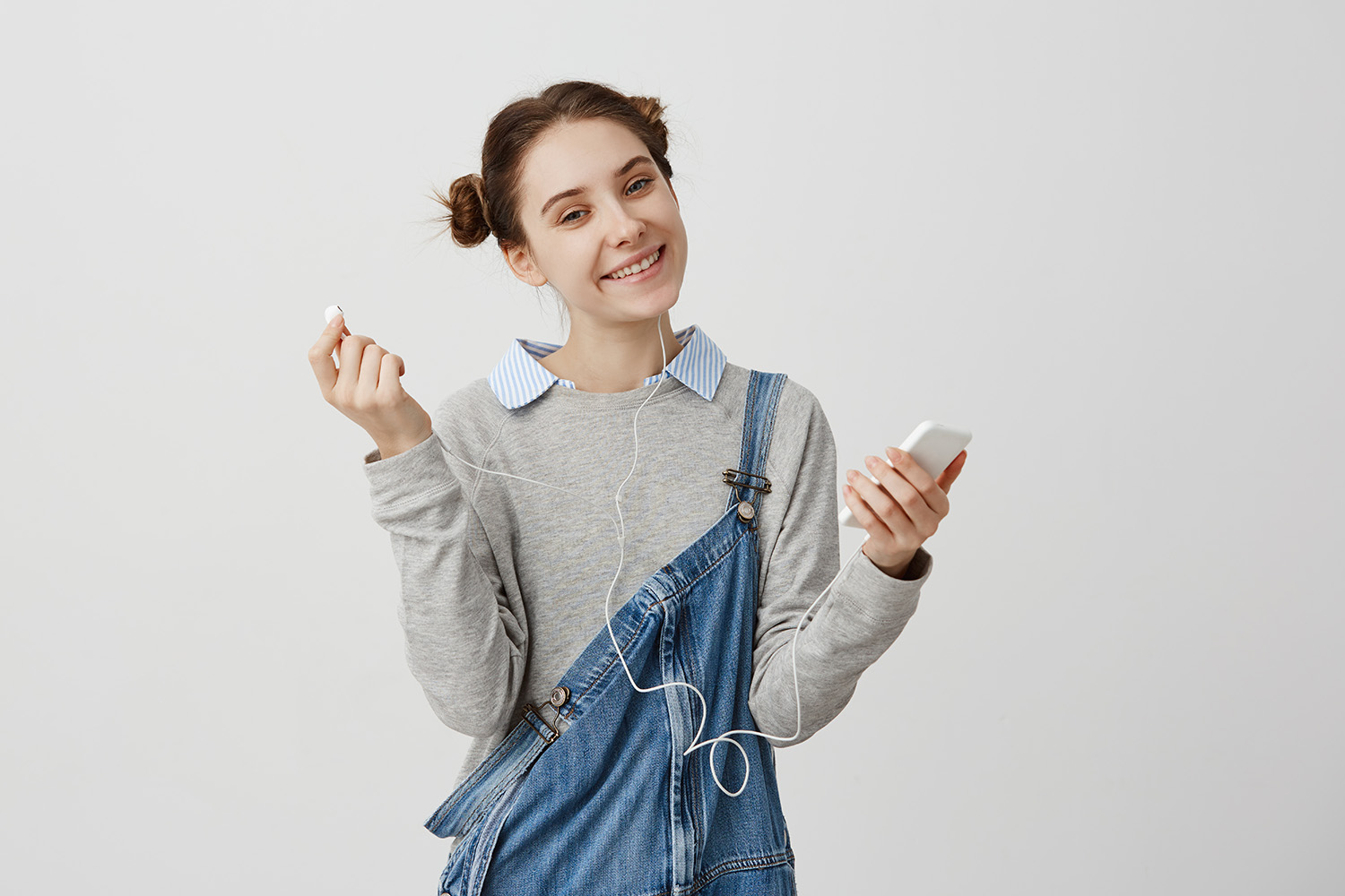 optimistic_girl_denim_holding_smartphone_looking_with_kind_smile.jpg
