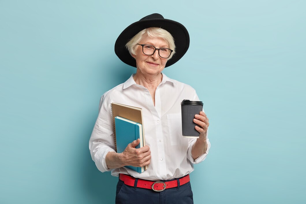 studying-old-age-pleased-wrinkled-woman-black-headgear-holds-two-notepads-takeaway-coffee-prepares-conduct-lectures-isolated-blue-wall-people-pension-drinking-concept_273609-26751.jpg